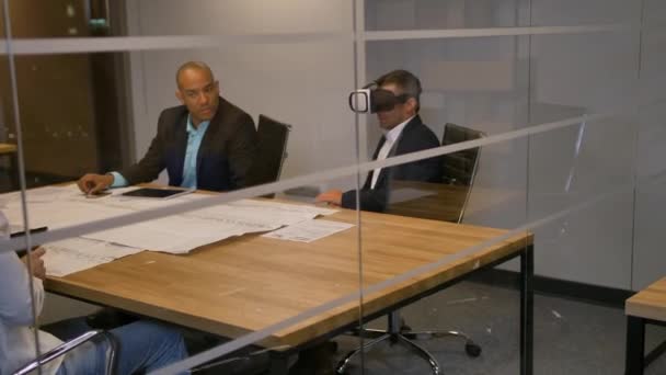 Equipe de negócios sentada em uma mesa, homem com óculos de realidade virtual. Pessoas testando fones de ouvido vr no escritório . — Vídeo de Stock