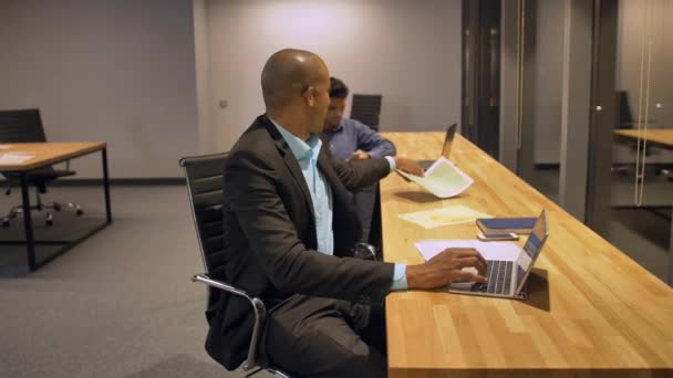 Empresario africano y su colega trabajando hasta tarde en la noche en su oficina con el ordenador portátil — Vídeos de Stock
