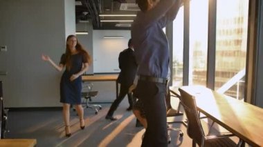 Bir grup iş adamı ofiste dans ediyor..