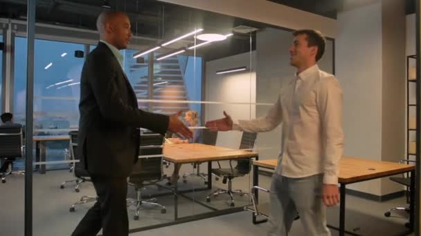 Two entrepreneurs shaking hands indoor in modern office. Aframerican and caucasian colleagues. — Stock Video