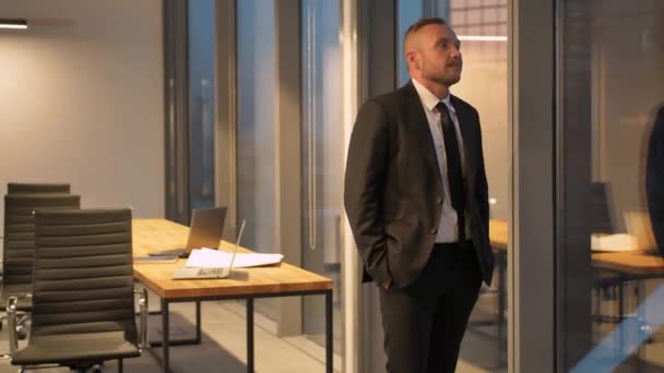 Tampilan depan pengusaha sukses dalam setelan berdiri di kantor dengan tangan di saku — Stok Video