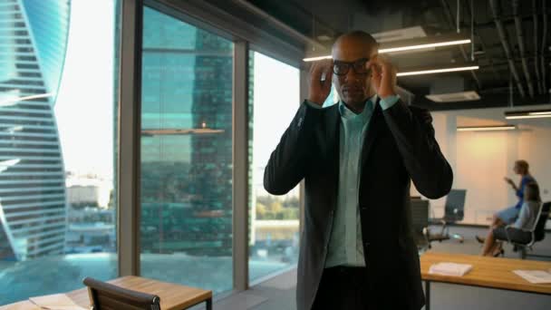 Empresario afroamericano poniéndose gafas y mirando a la cámara — Vídeo de stock