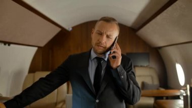 Özel jet iş yolculuğu konsepti. İşadamı cep telefonuyla konuşuyor.