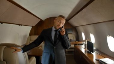 İş adamı özel jet kabininde telefonla konuşuyor.