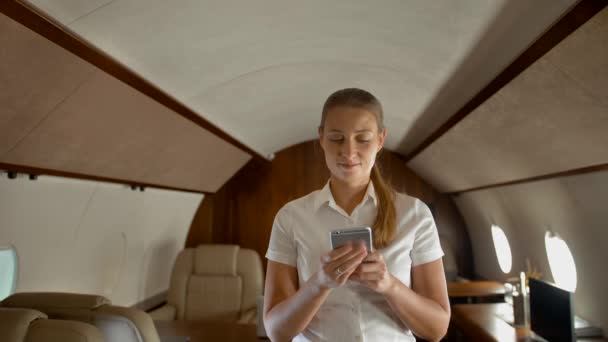 Απασχολημένη νεαρή γυναίκα πληκτρολογώντας μηνύματα στο smartphone σε ιδιωτικό τζετ. — Αρχείο Βίντεο