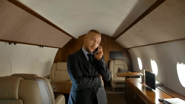 Empresario hablando en el teléfono celular interior de cabina de jet privado — Vídeos de Stock