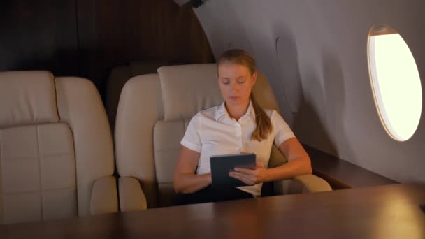 Mujer de negocios con tableta PC dentro del jet de negocios — Vídeos de Stock