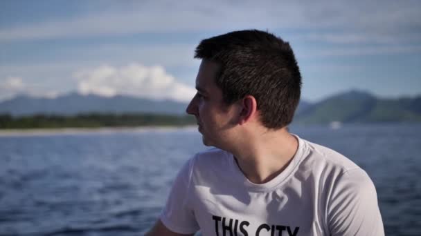 Mladý muž sedí v rychlodním člunu na převoz na slunečný ostrov — Stock video