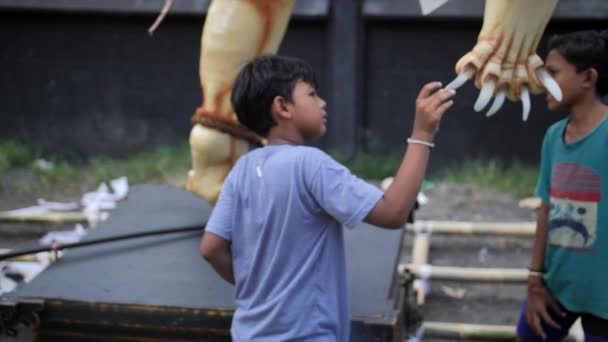 Balinesisches Kind untersucht eine aufblasbare Puppe eines nationalen bösen Geistes auf einem Karneval — Stockvideo