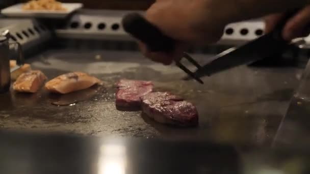 Asiatico chef slising carne per il pubblico su un grande stufa — Video Stock