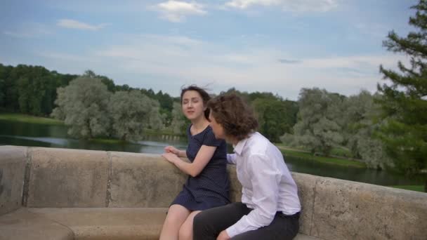 Deux jeunes amoureux s'embrassent sur un banc de pierre . — Video