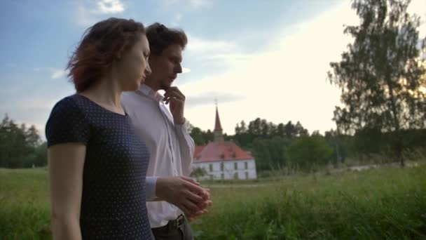 Een jong stel in Love Walks met het Gatchina Priory Palace op achtergrond. Grren quiet Park. — Stockvideo