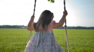 Biraz uzun saçlı kız arka tarafı görünümü, alanında bir ipli salıncak üzerinde sallanan