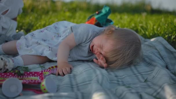 Küçük bir buçuk yaşındaki kız bir açık hava pikniğinde ağlıyor. — Stok video