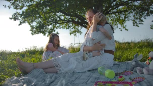 Een jonge mooie brunette moeder kalmeert haar dochter in haar armen. — Stockvideo