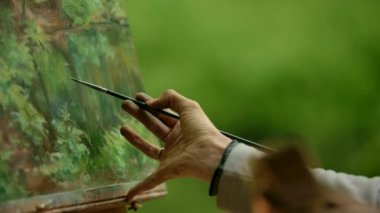 Bir kızın yakın çekim bir fırça ile boyama üzerinde son rötuşları yapan bir sanatçı el.