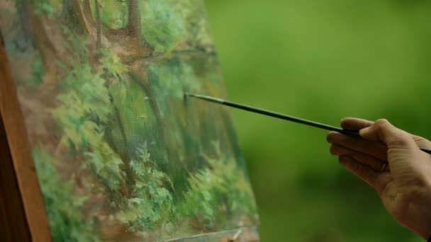 Närbild av en dam hand en konstnär med en pensel gör finishen över målning. — Stockvideo