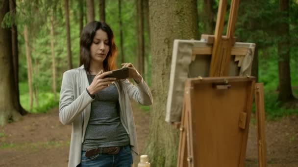 Γυναίκα καλλιτέχνης παίρνει μια εικόνα της ζωγραφισμένη εικόνα της σε ένα smartphone — Αρχείο Βίντεο