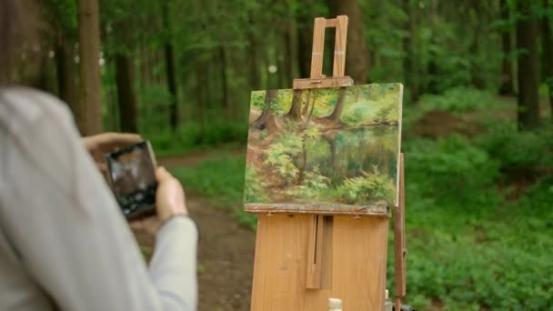 Привлекательная брюнетка рисует пейзаж под открытым небом в лесу и фотографирует — стоковое видео