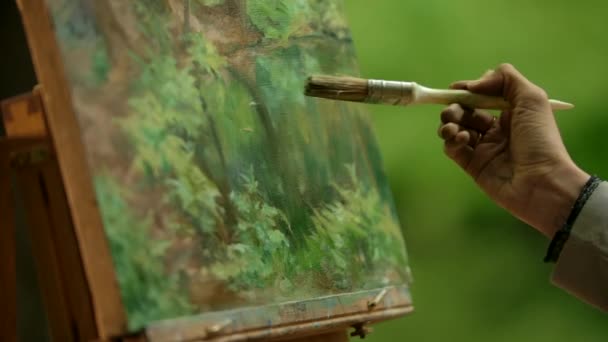 Primo piano di una ragazza palma un artista con un pennello facendo i tocchi sfocati sul suo dipinto . — Video Stock