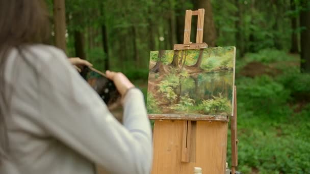Приваблива брюнетка леді малює пейзаж на відкритому повітрі в лісі і фотографує — стокове відео