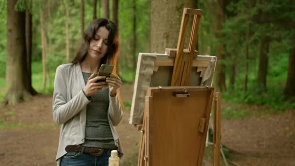 Przednia środkowa rama artysty dziewczyna z telefonem komórkowym w parku. — Wideo stockowe