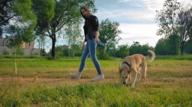 Kotlu, deri ceketli, köpeğiyle parkta gezen çekici bir kız.. 