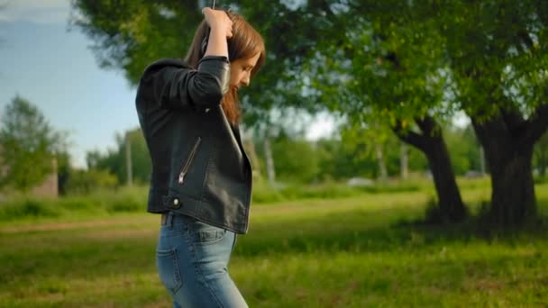 Une jeune femme met de gros écouteurs noirs et allume la musique sur son smartphone . — Video