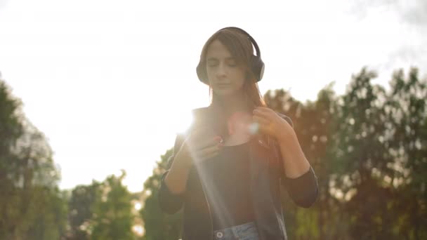 Portret van een jonge vrouw zet een koptelefoon op en zet de muziek aan. Muziekliefhebber concept. — Stockvideo