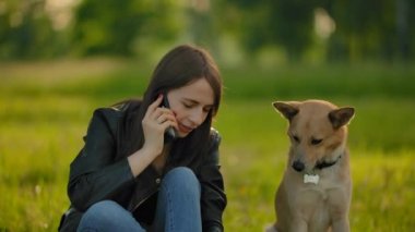 Parkta köpek gezdirirken telefonda konuşan bir kız..