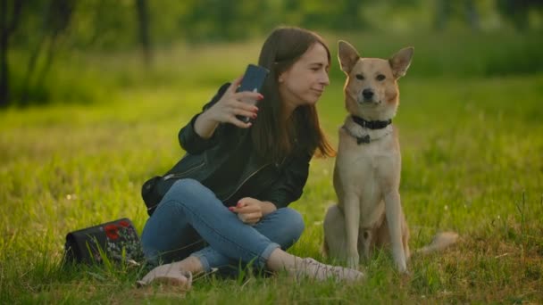 Ragazza fa selfie su uno smartphone accanto al suo cane . — Video Stock