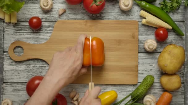 Mužská ruka krájí papriku nožem ve dvou. — Stock video