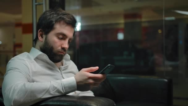 Νέοι άνδρες ελέγχει τα κοινωνικά δίκτυα σε ένα κινητό τηλέφωνο, ενώ περιμένουν για ένα κούρεμα. — Αρχείο Βίντεο