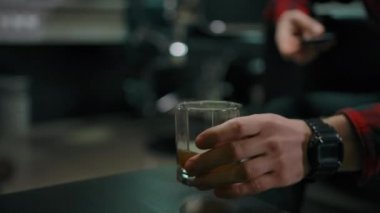 Saçını kestirmek için sırada bekleyen genç bir adam birkaç yudum viski içer.