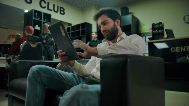 Young bearded caucasian man checking socials on a tablet PC — Stock Video