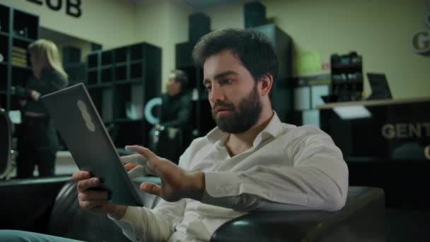 Ung kaukasisk man kontrollera sociala medier på en tablett PC — Stockvideo