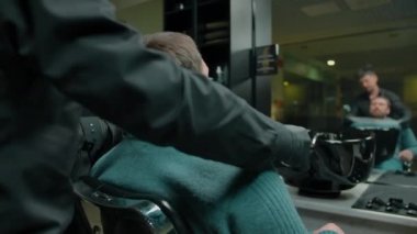 Berber müşteriyi saç kesimine hazırlar, peçete bağlar.