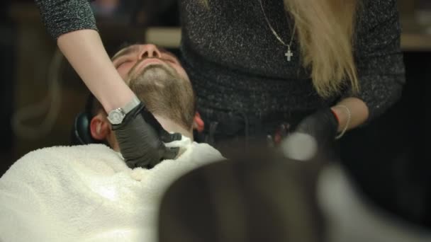 Blondie kvinna frisör klippa skägg hår på sin klient med rak rakkniv — Stockvideo