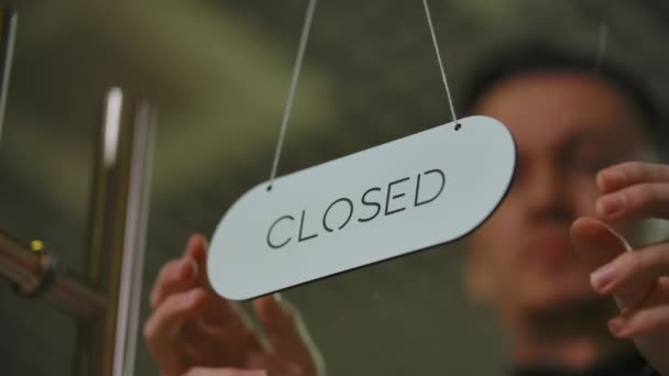 Close-up of young barber turning door closed nameplate to open. — Stock Video