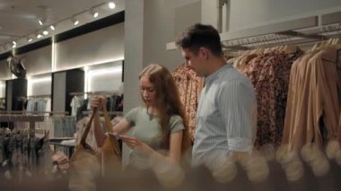 Kadın ve erkek moda mağazasında yürüyorlar.