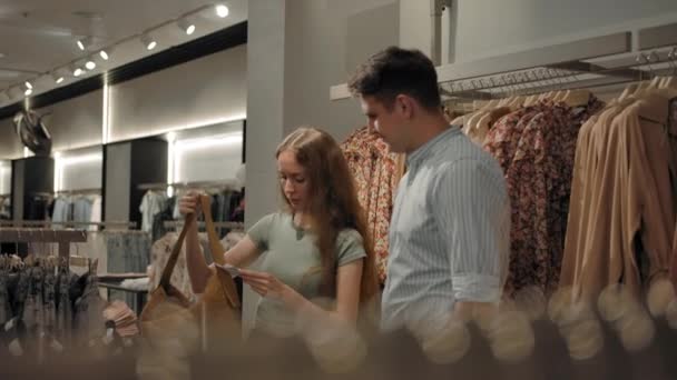 Hombre y mujer caminando en interiores de la tienda de ropa de moda — Vídeo de stock