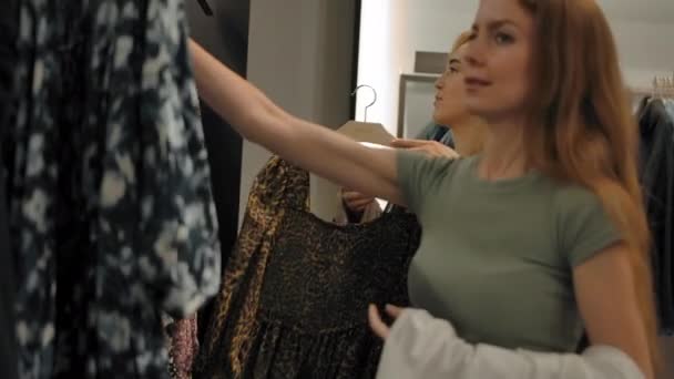 Dos amigas eligiendo ropa en una tienda de ropa — Vídeos de Stock