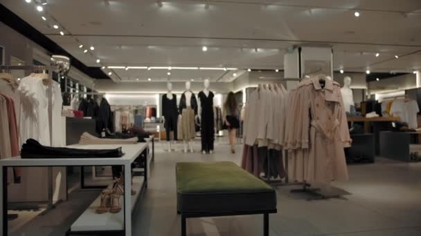 Тайм-ап магазина пустой одежды с двумя покупательницами, выбирающими одежду — стоковое видео