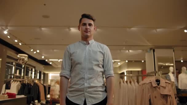 Портрет улыбающегося мужчины в летней рубашке в помещении модного магазина одежды — стоковое видео