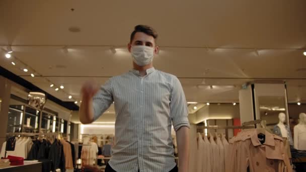 Młody mężczyzna wyrzucający maskę w sklepie z ubraniami, pandemia covid-19 się skończyła. — Wideo stockowe