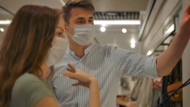 Maskeli kadın ve erkek, salgın sırasında modern mağazayı ziyaret ediyor.