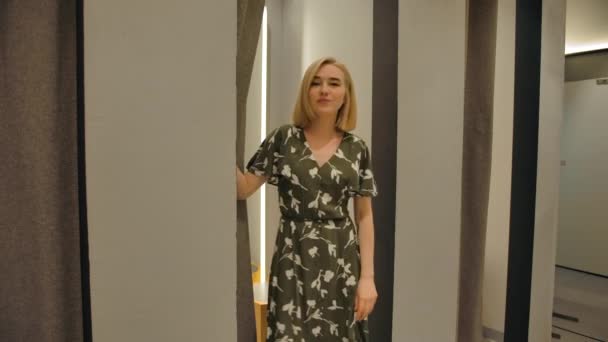 Blondie Mädchen zieht Vorhang zurück und zeigt unterschiedliche Kleider, hübsche Frau — Stockvideo
