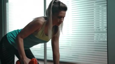 Spor sıralarında diz çökmüş triseps egzersizi yapan seksi kadın.