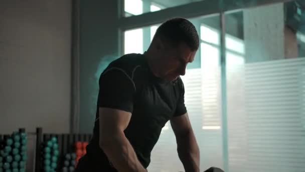 Handheld shot of muscular man hardly working out with heavy dumbbells in gym — Stock Video