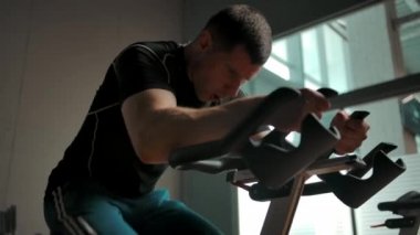 Kafkas sporcusu spor salonunda sabit bir bisiklette pedal çeviriyor.